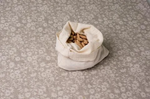 Bones of a plum in a canvas bag on the background of a linen gray tablecloth Stock Photos