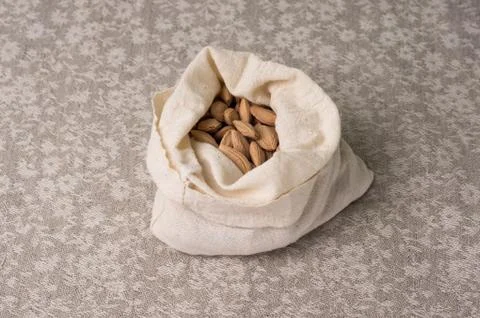 Bones of a plum in a canvas bag on the background of a linen gray tablecloth Stock Photos