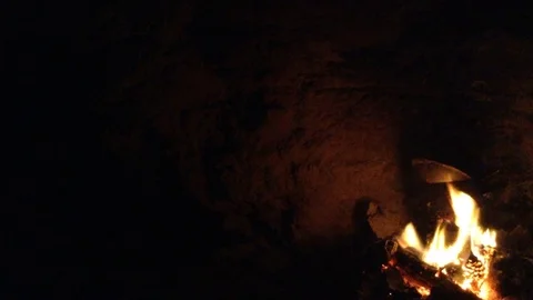 Bonfire burning in the dark cave and utensils Stock Footage 73678952