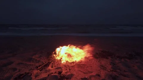 Bonfire Burning on a Dark Sandy Beach at Twilight near the Ocean Stock Footage 331280892