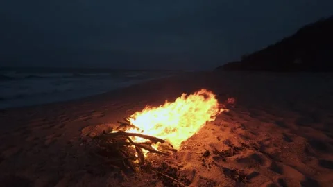 Bonfire Burning on a Dark Sandy Beach at Twilight near the Ocean 库存影片 331281000