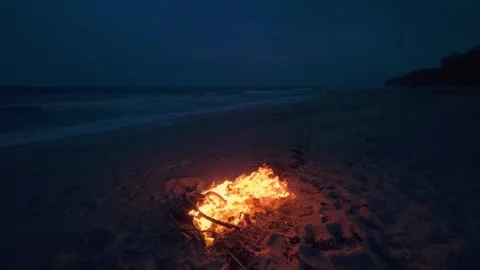 Bonfire Burning on a Dark Sandy Beach at Twilight near the Ocean 库存影片 331281018