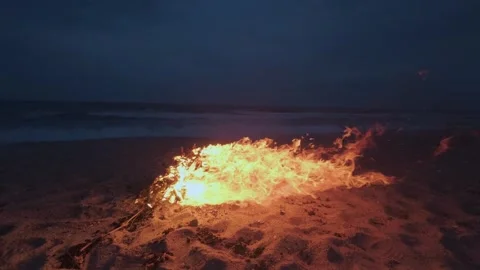Bonfire Burning on a Dark Sandy Beach at Twilight near the Ocean 库存影片 331281027