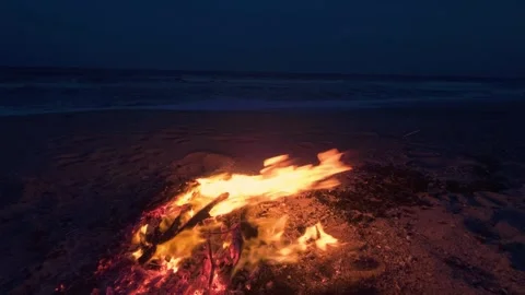Bonfire Burning on a Dark Sandy Beach at Twilight near the Ocean 库存影片 331281127