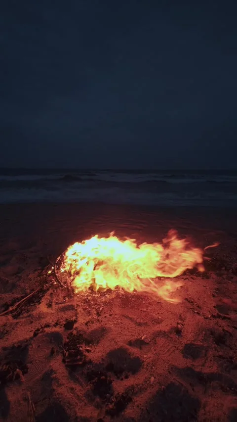 Bonfire Burning on a Dark Sandy Beach at Twilight near the Ocean Stock Footage 331533874