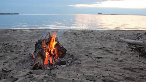 Bonfire burning on the riverbank  on the sunset Stock Footage 80939406
