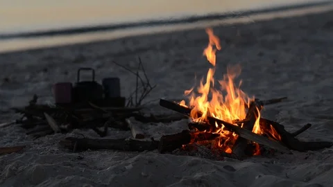 Bonfire burns on the beach next to waves Stock Footage 96736433