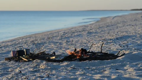 Bonfire burns on the seashore next to waves Stock Footage 96736424