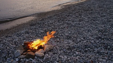 Bonfire on the pebble seashore in the evening Stock-Footage 125475628