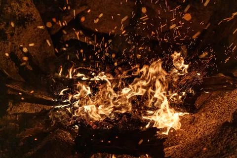 Bonfire with sparkles by the rock. Stock Photos