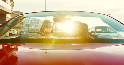 Bonnet view of a young beautiful mixed couple driving in a red car with roof low Stock-Footage 229744935