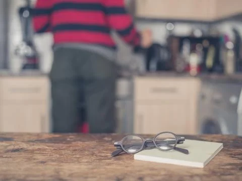 Book and glasses on table in kitchen Foto stock