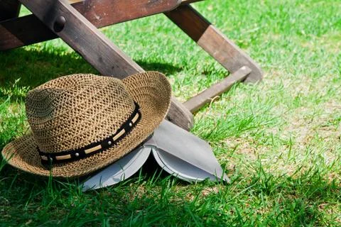 Book and straw hat on grass Stock Photos