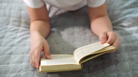 Book in boy's hands. close-up view from above. turns pages Stock Footage 306445410