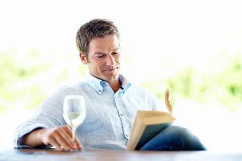 Book, knowledge and happy man with wine glass on break, reading and chill w.. Stock Photos