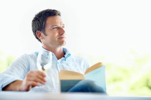 Book, knowledge and happy man with wine glass, thinking and relax with nove.. Stock Photos