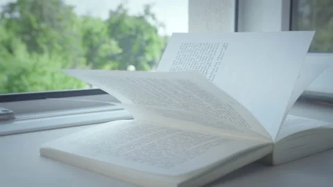 A book lies on the windowsill of an open window, the rays of the sun on the Stock Footage 160307634