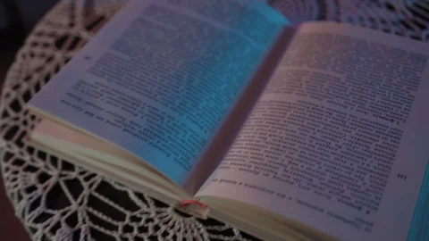 The book is lying on the table in a colored light. .the frame is getting closer Stock Footage 128458486