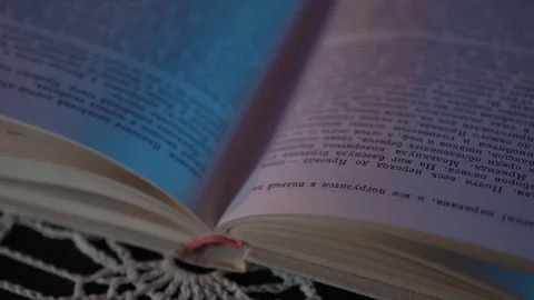 The book is lying on the table in a colored light. .the frame is getting closer Stock Footage 128458592
