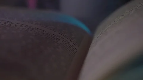 The book is lying on the table in a colored light.the frame is getting closer Stock Footage 128460277