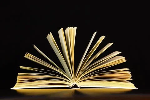 The book is open on a black background. Stock Photos