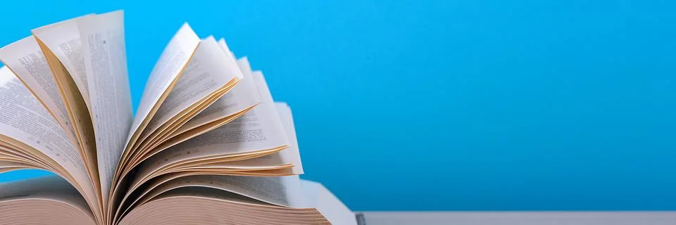 The book is open, lying on the table, sheets fanned out on a blue background. Stock Photos
