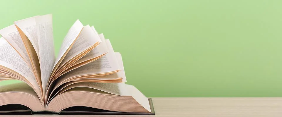 The book is open, lying on the table, sheets fanned out on a green background Stock Photos