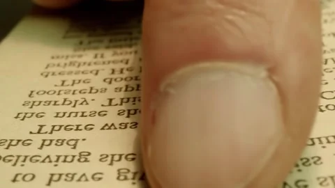 A book open on a table and a man's finger moves along the lines of texts Stock Footage 297748587