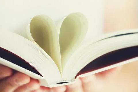Book with opened pages and shape of heart in girl hands. Copy space. Love Stock Photos