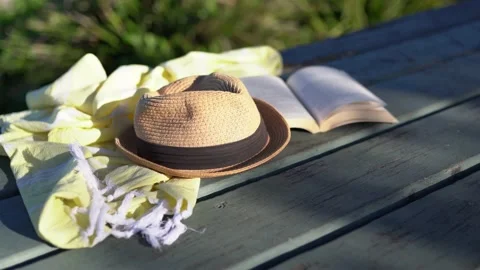 Book, shawl and a hat on the table with a lonely ocean beach in a background. Stock Footage 134505570