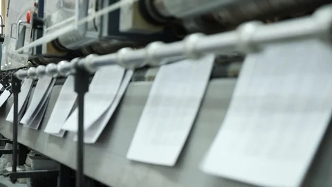 Book sheets fall on the tape and move along a conveyor belt to a print shop. 動画素材 98115404