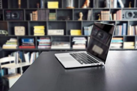 Book stack and notebook computer on table in library room with blurred booksh Stock-Fotos