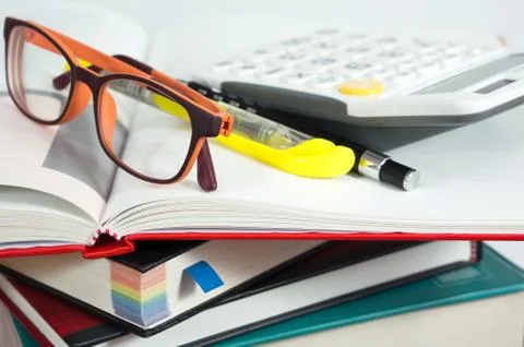 Book stack with eyeglasses and calculator Stock Photos