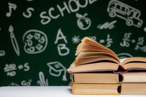 Book stack on a green blackboard background, back to school concept Stock Photos