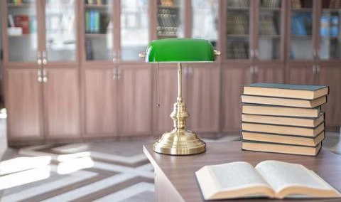 Book stack on wood desk and blurred bookshelf in the library room. Stock Photos