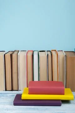 Book stacking. Open book, hardback books on wooden table and blue background. Stock-Fotos