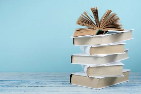 Book stacking. Open book, hardback books on wooden table and blue backgroun.. Stock Photos