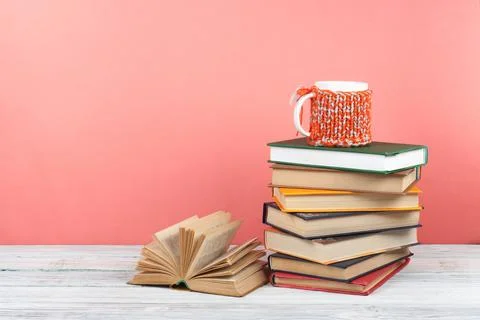 Book stacking. Open book, hardback books on wooden table and pink background. Stock Photos