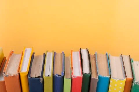Book stacking. Open hardback books on wooden table and yellow background. Bac Foto stock