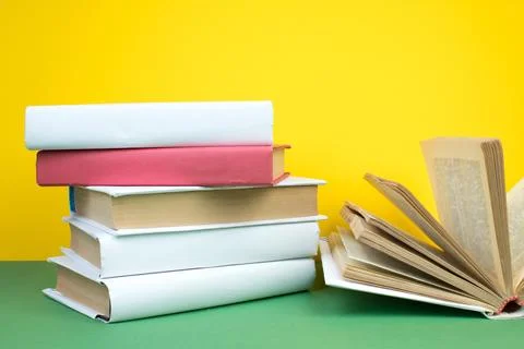 Book stacking. Open hardback books on wooden table and green background. Back Stock Photos