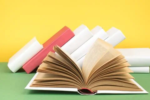 Book stacking. Open hardback books on wooden table and green background. Ba.. Stock Photos