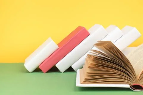 Book stacking. Open hardback books on wooden table and green background. Back Stock Photos
