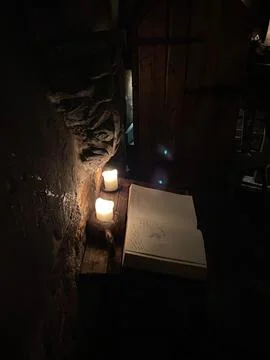 A book is on a table with candles lit Stock Photos
