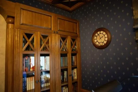 Bookcase in the office of the head. A clock hangs on the wall. Stock Photos