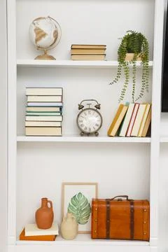 Books and different decorative elements on shelves indoors Foto stock