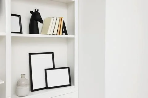 Books, frames and different decorative elements on shelving unit indoors, s.. 스톡 사진