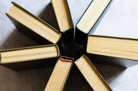 Books with multi-colored covers are stacked in a circle top view. Stock Photos