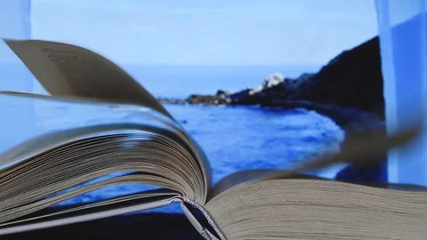 Book's pages turning by wind on table in terrace window with sea ocean view Stock Footage 128522223
