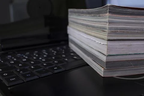 Books stack on a black laptop keyboard, abstract jurnalism concept Stock Photos