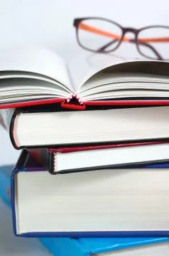 Books stack with open book and reading glasses Stock Photos